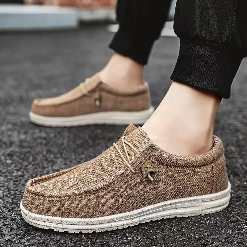 Chaussures décontractées de type mocassins à enfiler en toile pour hommes, de couleur beige, avec des lacets beige clair et une semelle en caoutchouc blanche.