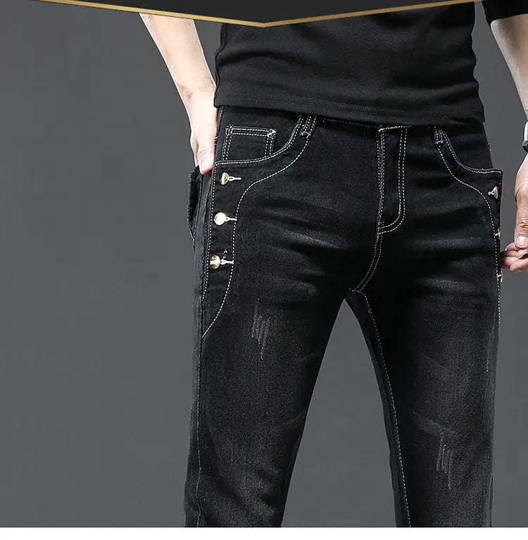 Jeans slim en denim extensible vintage pour hommes, lavage gris, avec denim noir, surpiqûres blanches et boutons argentés décoratifs le long de la couture latérale.