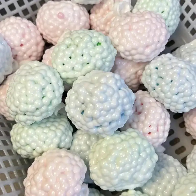 Pastellrosa und minzgrüner glänzender Stressball mit strukturierter, buckeliger Oberfläche, entworfen als knisterndes Fidget-Spielzeug für ASMR und zur Stresslinderung.