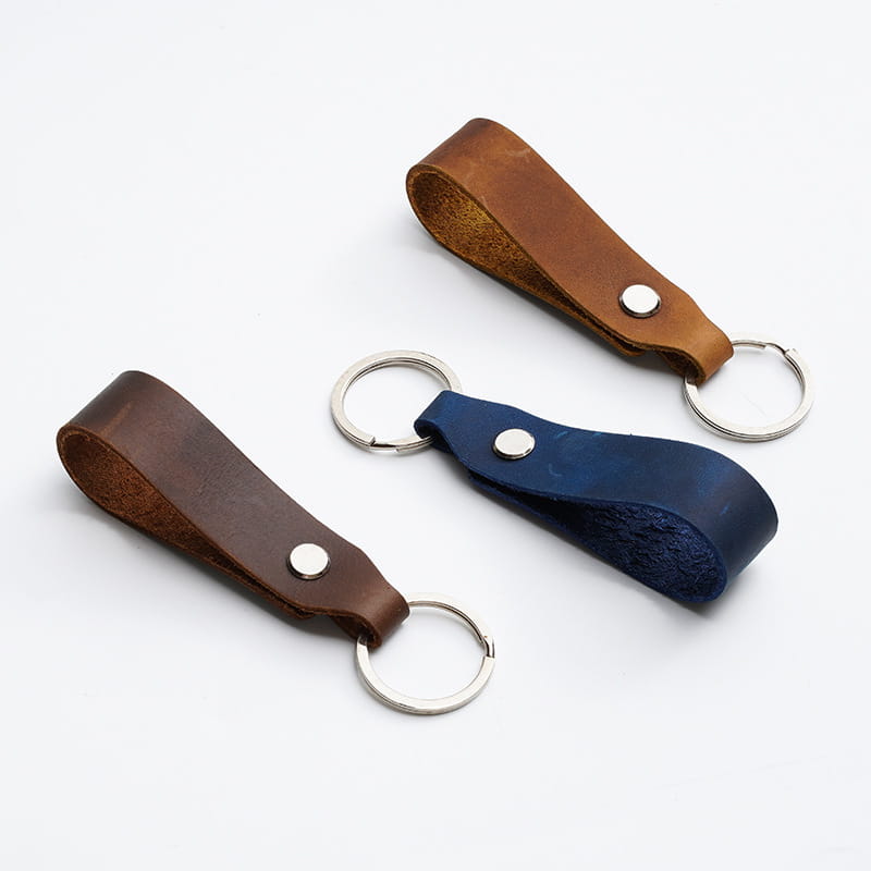 Three leather car keychains in brown dark blue and medium brown with silver-toned metal rings and rivets for genuine lanyard key holders.