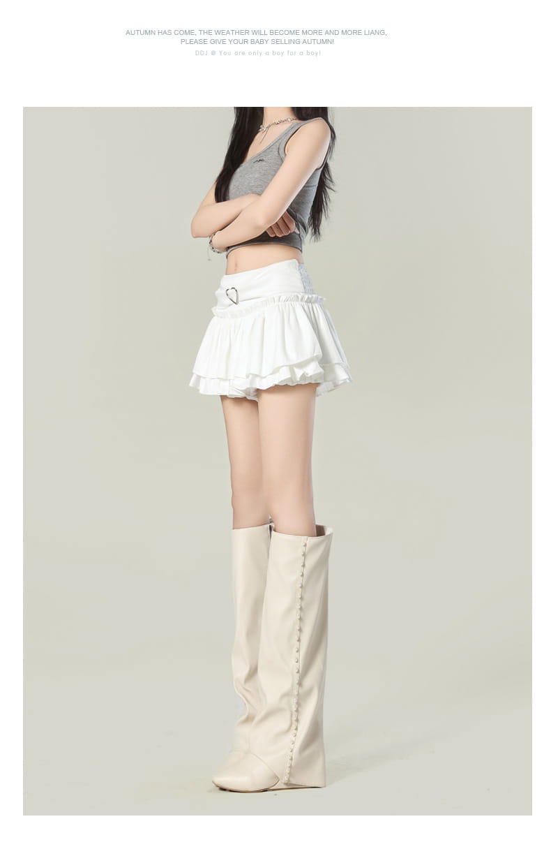White pleated high waist mini skirt with ruffles and a heart-shaped belt buckle in Y2K style.