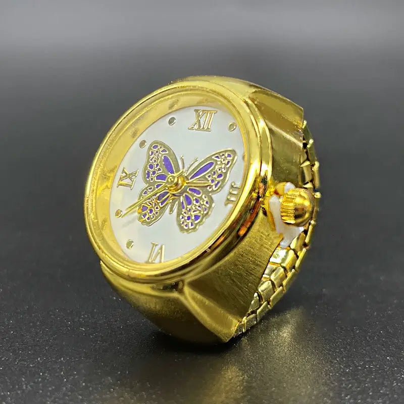 Gold butterfly watch ring in stainless steel with a gold color, white dial featuring roman numerals, and a purple enamel ornate butterfly design at the center.