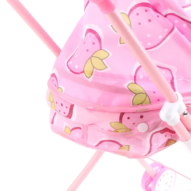 Rosa Puppenwagen für 12-Zoll-Babypuppen mit einem Kunststoffrahmen mit weißen Akzenten und erdbeermusterndem Stoff.