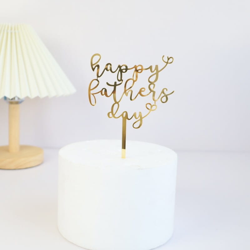 Father’s Day acrylic cake topper with gold metallic happy fathers day lettering in delicate cursive script and heart accents for super dad celebration.