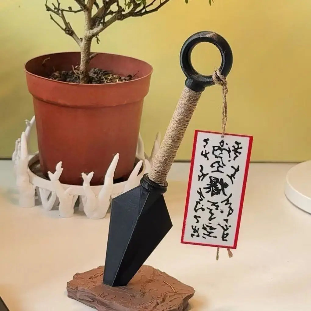schwarzer Papier-Ninja-Stern mit umwickeltem Griff und schwarzem Ring, dargestellt auf steinernem Sockel, als Ninja-Kunai-Kühlschrankmagnet aus PVC, Shuriken-Spielzeug
