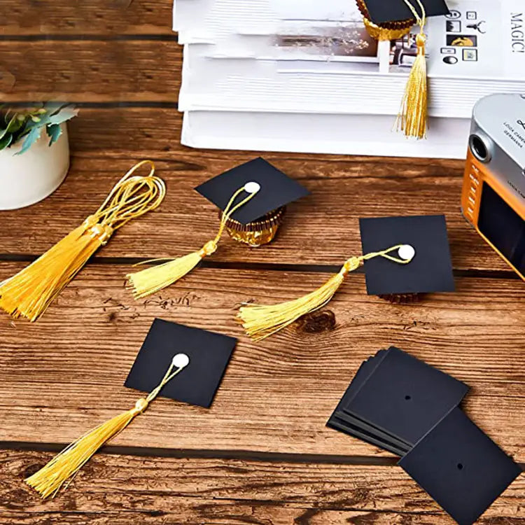 decoraciones de chocolate y caramelos con temática de birrete de graduación negro, con borlas doradas y detalles de botones blancos para celebraciones de graduación 2025