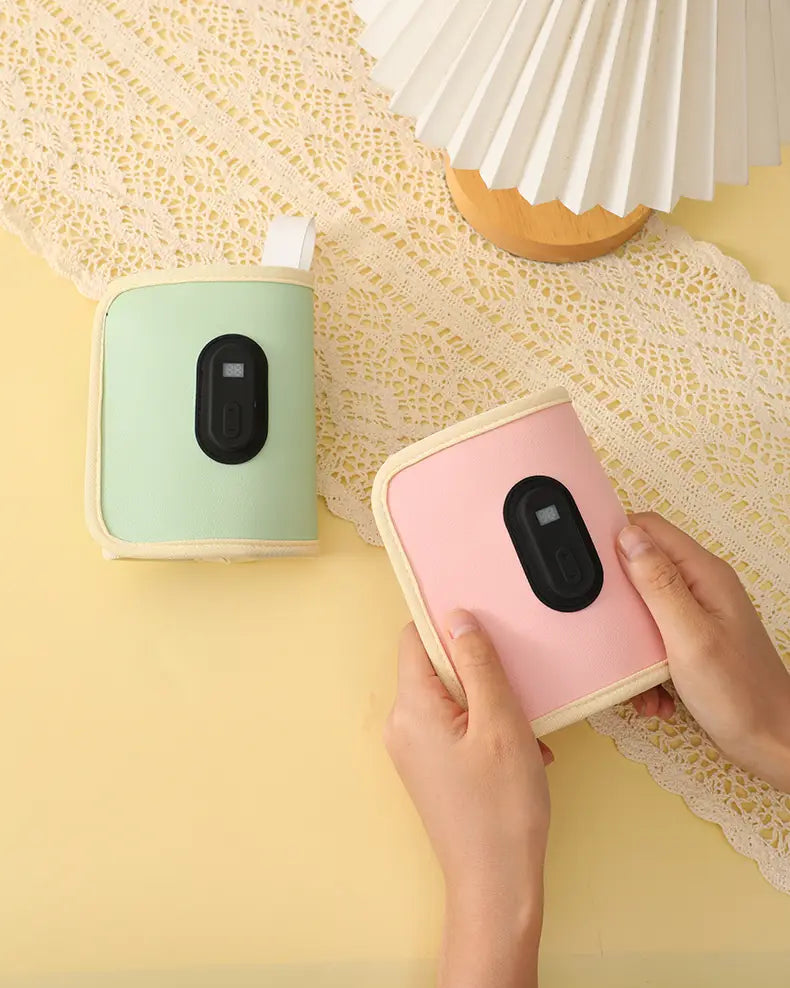 Tragbare USB-Babyflaschenwärmer in Pastellgrün und -pink mit cremefarbenem Rand und schwarzen ovalen Knöpfen, ausgelegt für ein bequemes Erwärmen.