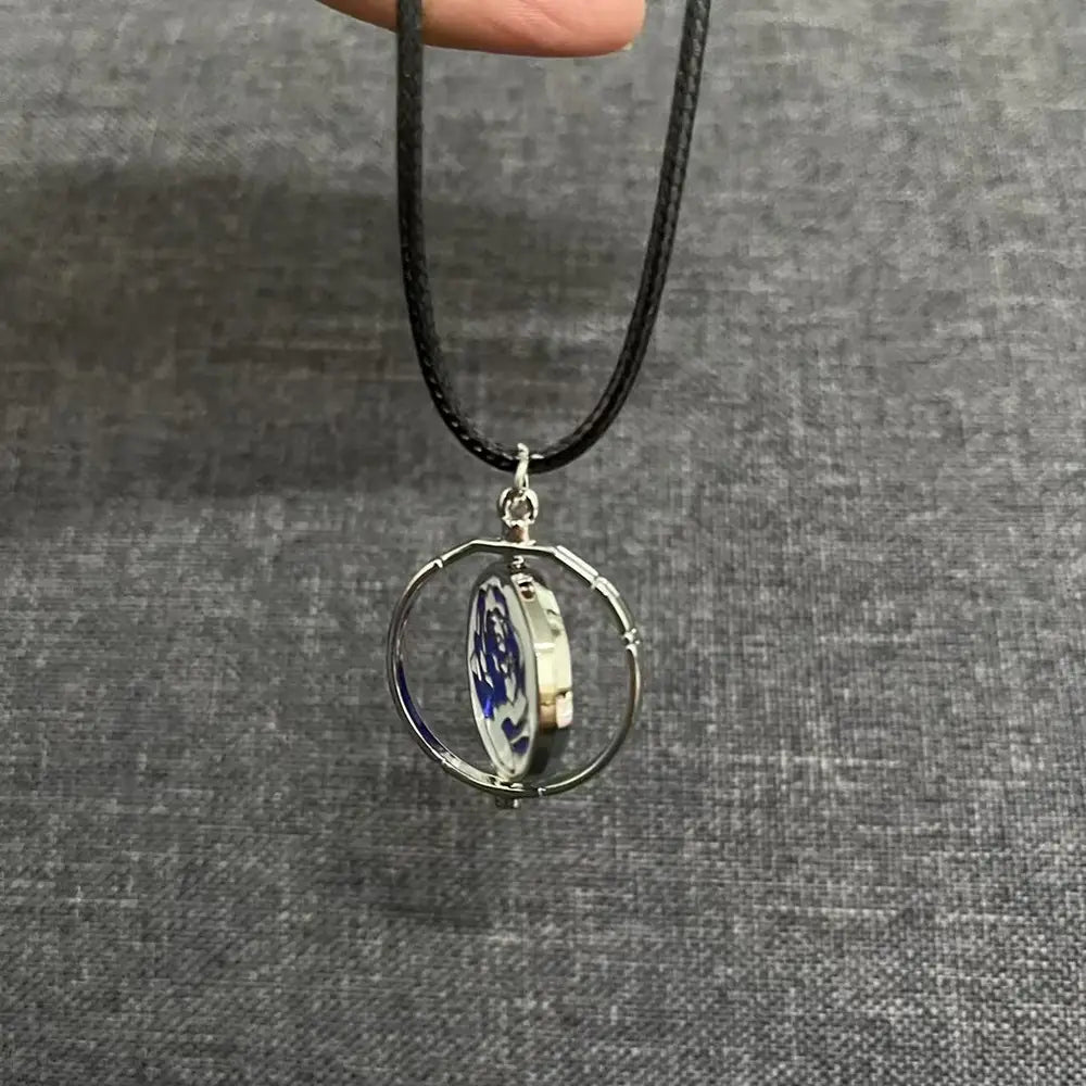 Silver-toned circular metal Jinx Cannon anime keychain pendant with a rotating inner disc featuring a blue and white porcelain-like design, suspended from a black cord.