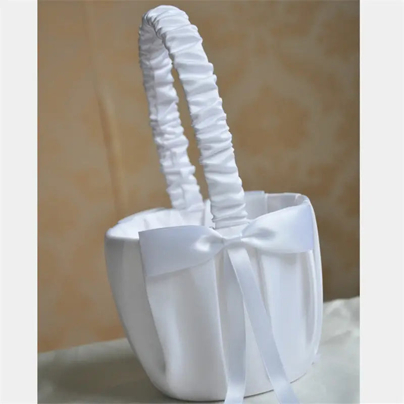 Panier de demoiselle d’honneur en satin blanc avec une anse froncée et un nœud perlé assorti.
