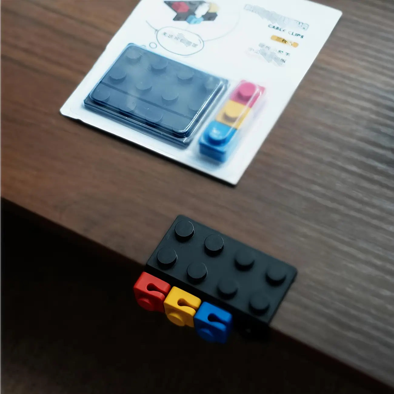 Modular brick cable organizer 2 sets featuring a black lego brick cable clip with red yellow and blue connector pieces designed for organized cable management.