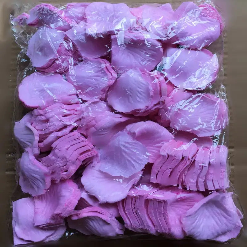 A package of 5500 colorful soft pink artificial rose petals made from lightweight fabric with delicate veining and layered edges for wedding decor.