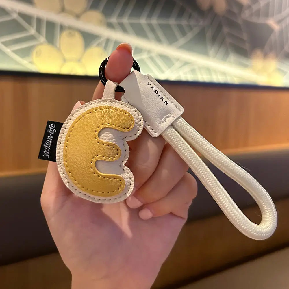 Yellow and white leather initial keychain wristband charm featuring a stylized letter e design.