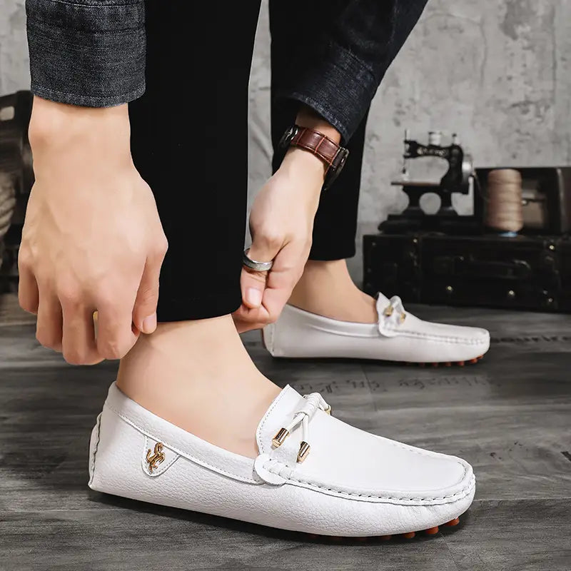 Les chaussures à enfiler habillées en cuir blanc pour hommes, avec des accents métalliques ton or et un design classique de mocassin pour un port décontracté sans effort.