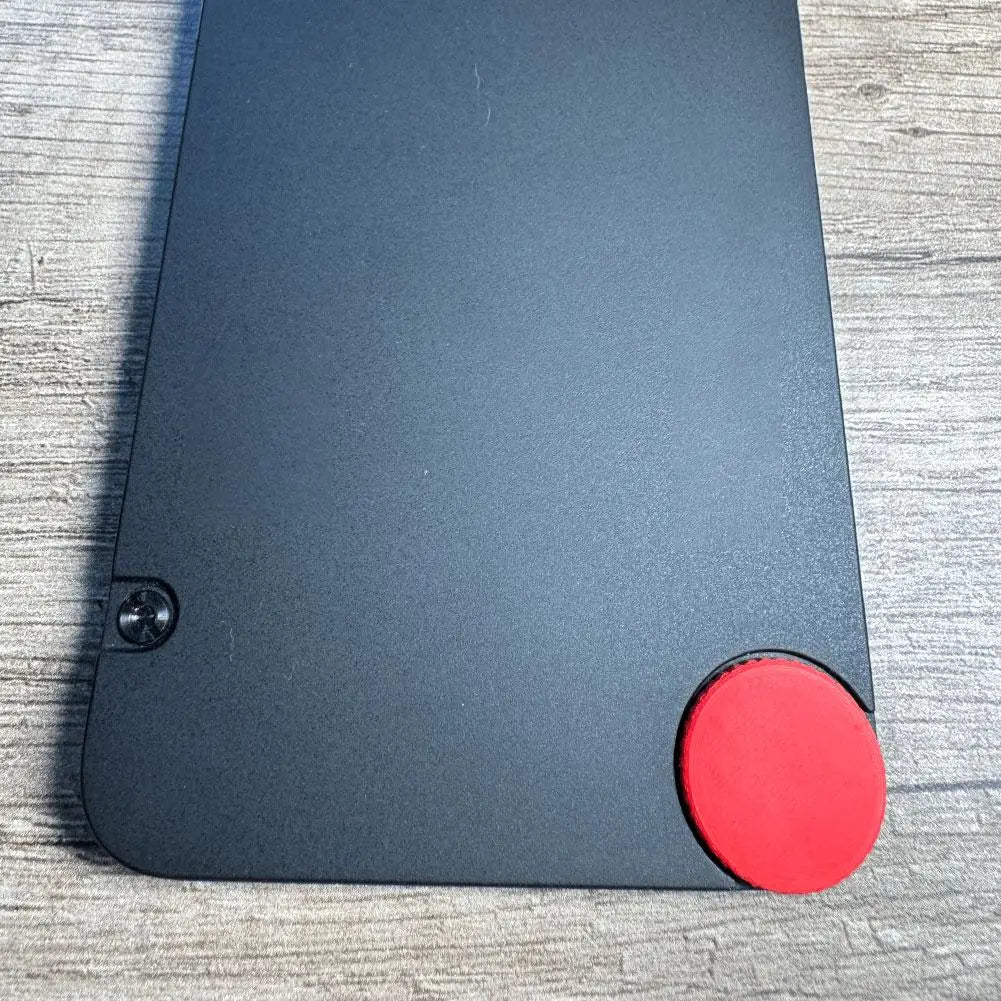 Ordinateur portable Lenovo ThinkPad noir, doté d’un capuchon de vis circulaire rouge pour accent personnalisé sur le coin inférieur droit, pour le remplacement du Cmf Phone 1.