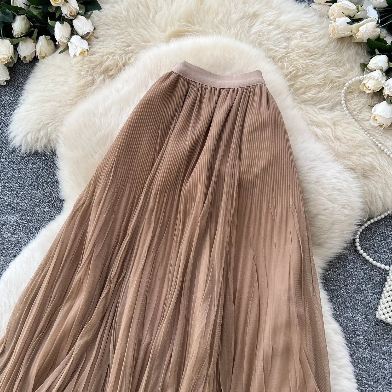 Ein fließender beigefarbener Plisseerock Midi mit weichem transparentem Stoff und elastischem Bund, entworfen im A-Linien-Stil für die Y2K-Streetwear-Mode.