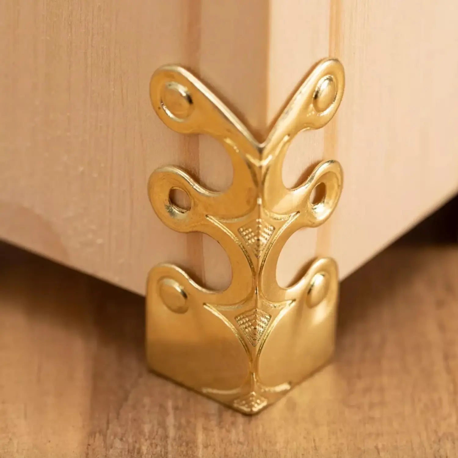 gold-colored metal corner protector with ornate leaf-like design for metal skirting board edge guards and corner protectors