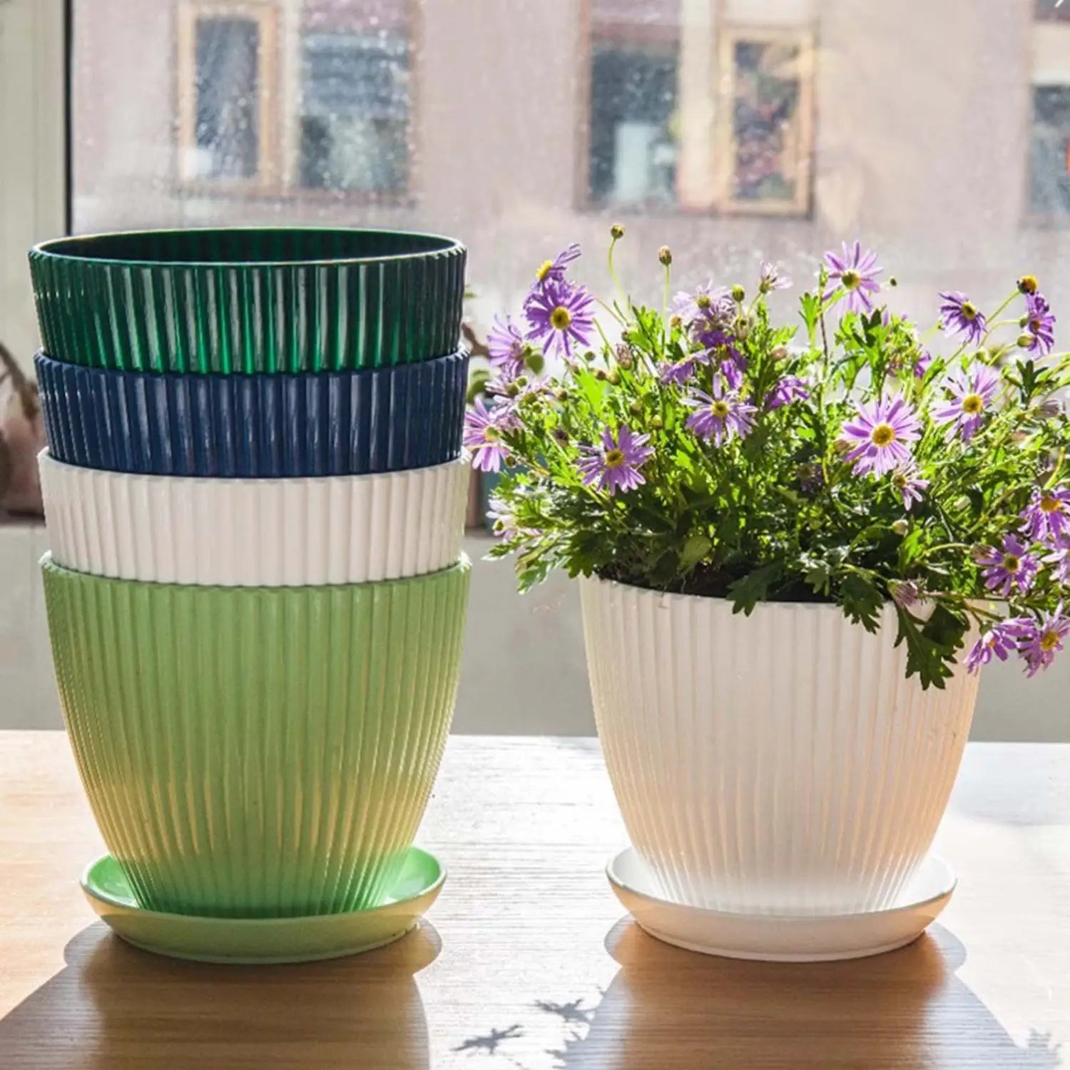 植物の栽培および屋内ガーデニング用に設計された、色鮮やかなリブ加工のプラスチック製育苗ポットと同じデザインの受け皿のスタック。
