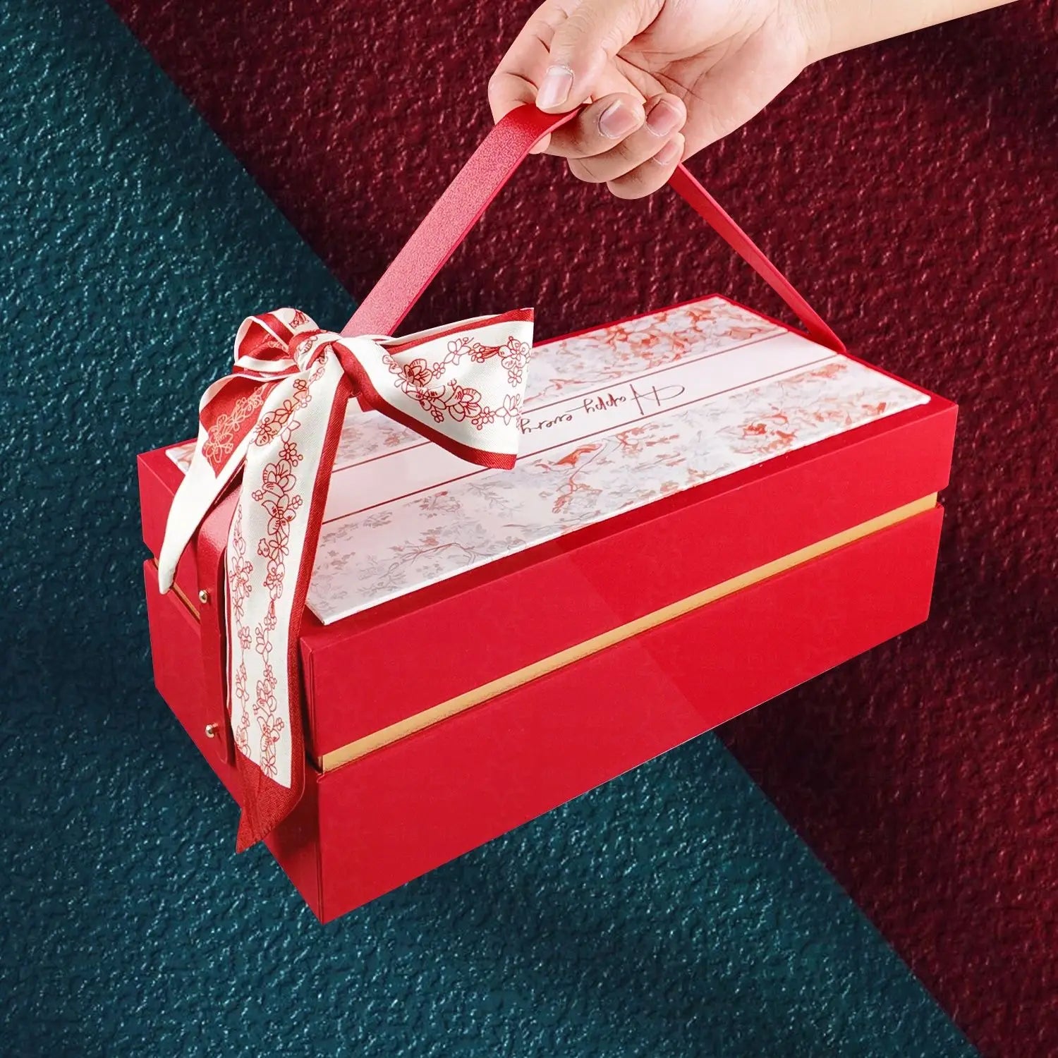 Un coffret-cadeau de mariage de luxe rectangulaire rouge brillant, avec une poignée assortie et un nœud décoratif en ruban floral blanc et rouge élégant sur le dessus, destiné à la demoiselle d’honneur et au meilleur ami.
