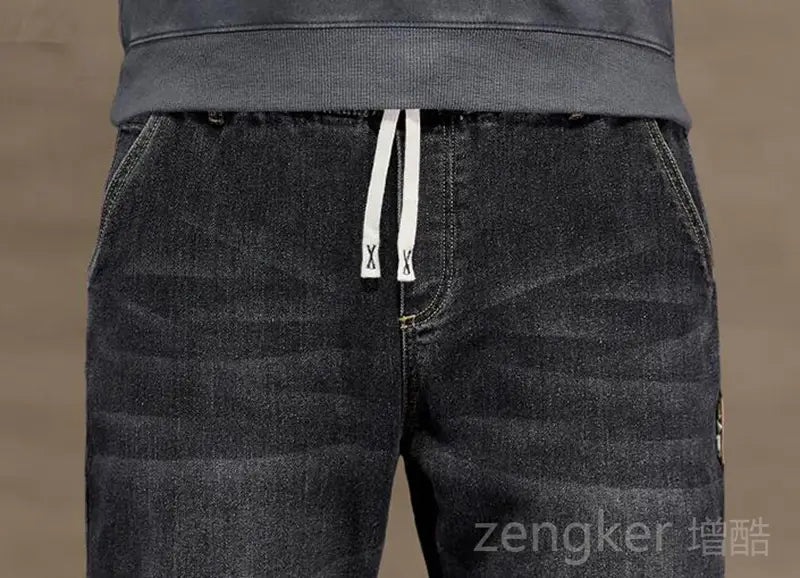 Plus size elastic waist loose straight jeans in dark-wash denim featuring white drawstring tabs with black x branding.