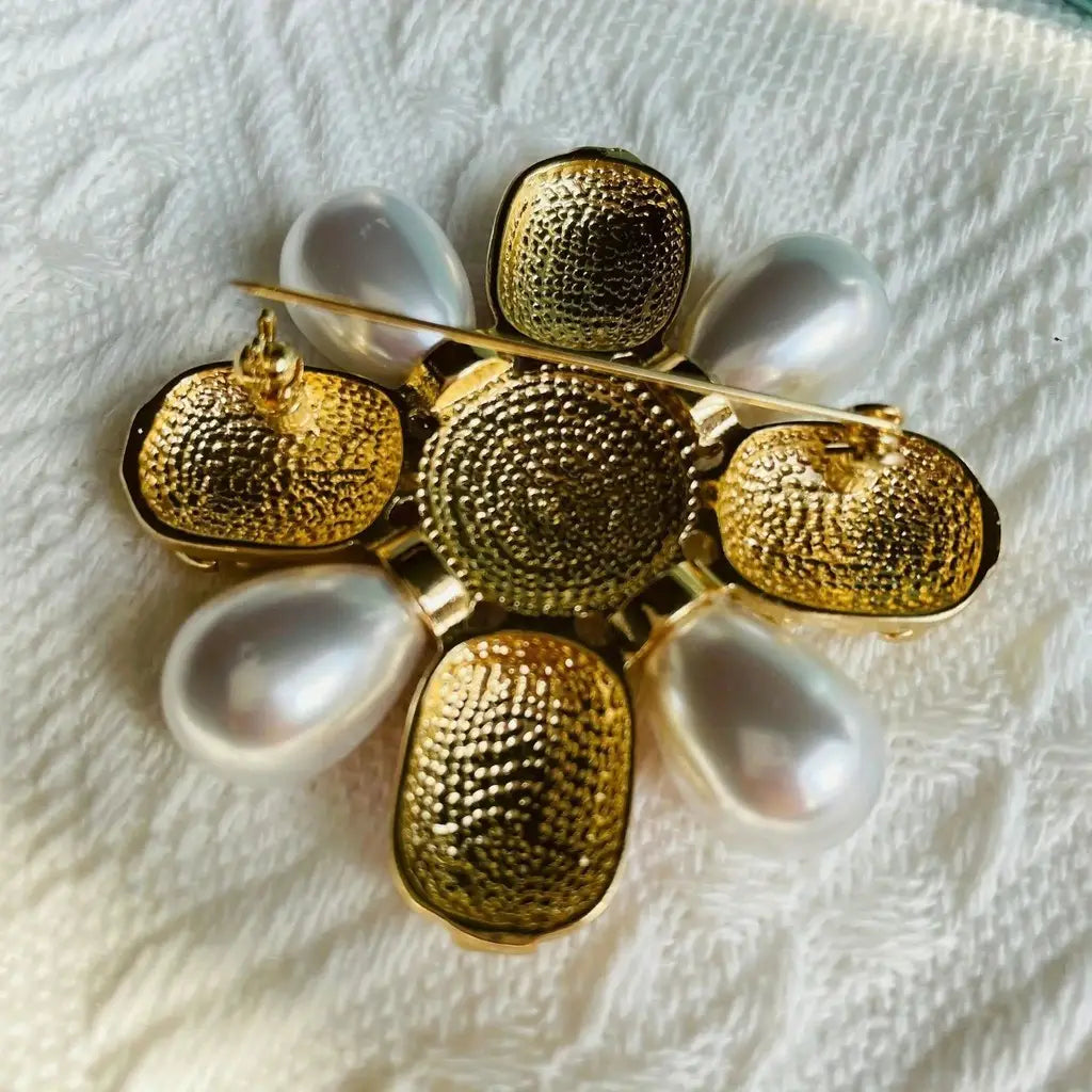 Broche fleur de perles designer à ton doré, aux pétales texturés et à des rehauts évoquant des perles.