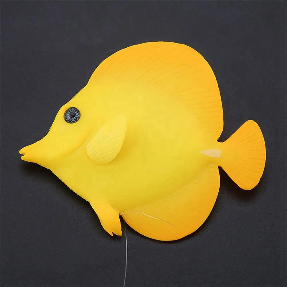 Ein leuchtend gelber künstlicher Fisch aus Silikon mit einem schwarzen, detaillierten Auge und einer dezenten Flossenstruktur für eine Aquarienzierde.