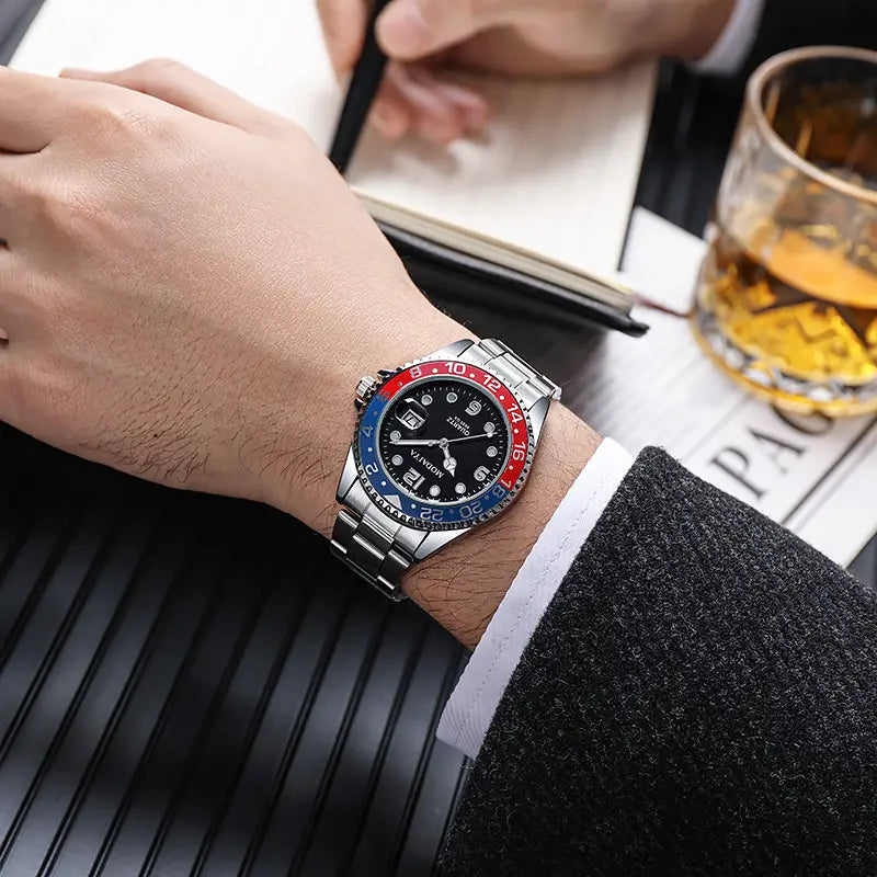 Quartz sport watch with a silver-toned stainless steel case, black dial, red and blue bezel accents, white hour markers, and a black rubber strap.