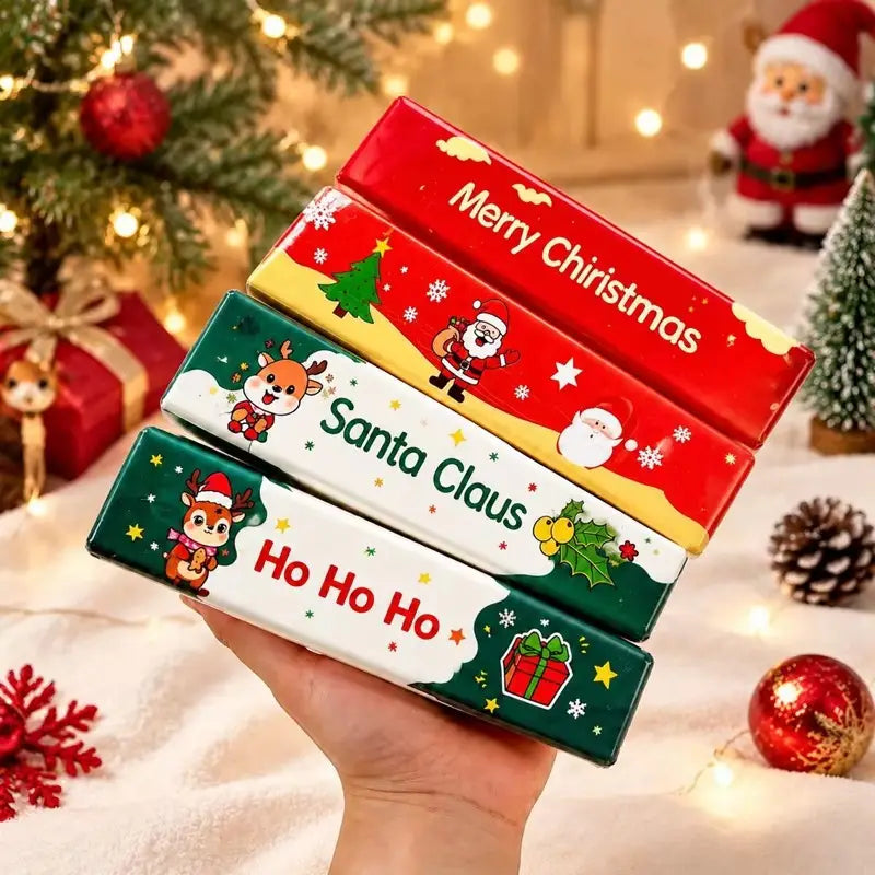 Una mano que sostiene cuatro juguetes antiestrés blandibles rectangulares festivos con tema de Santa Claus de Navidad, con diseños coloridos de temporada y texto «Feliz Navidad» y «Santa Claus».