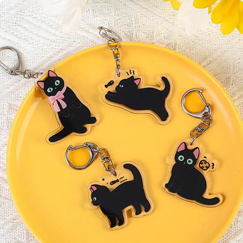 Black acrylic cat keychains with pink accents and silver metal clasps used as cartoon animal bag charms.