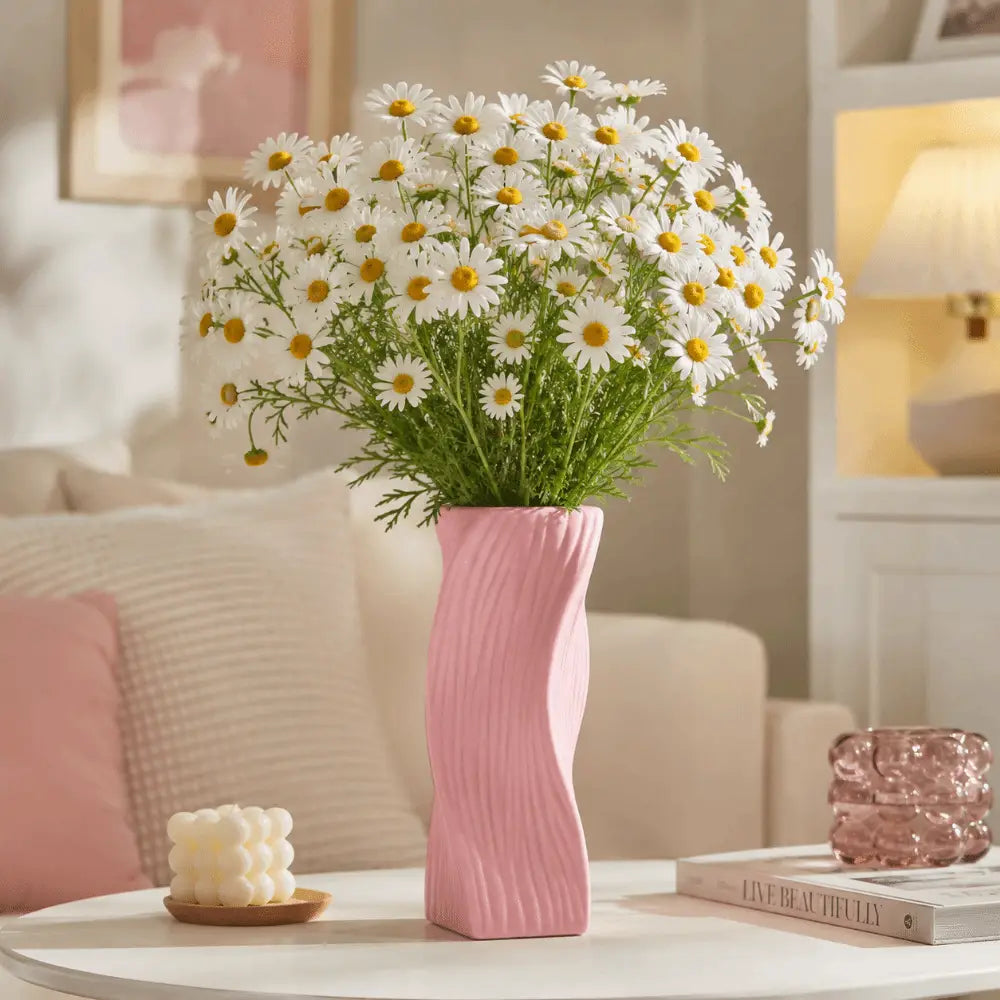 A pink ceramic Nordic wave plastic flower vase with a wavy ribbed texture holding a bouquet of white daisies for aesthetic home decor.