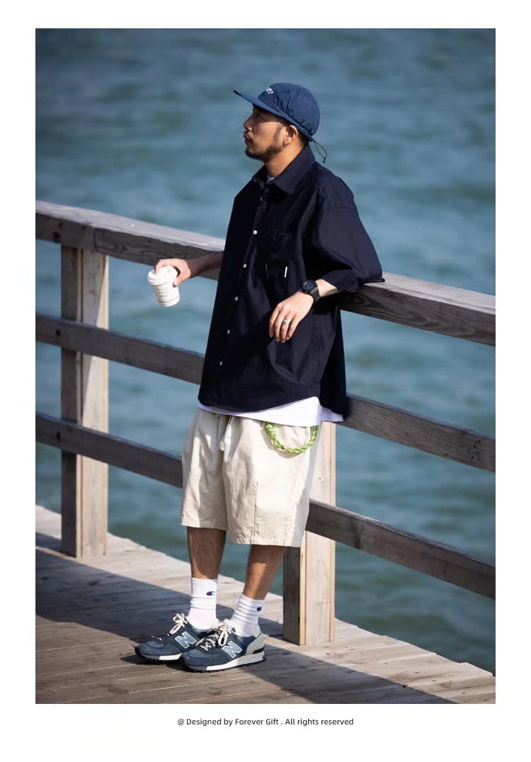 Mens casual short sleeve button up shirt paired with navy blue New Balance 990v4 sneakers featuring white laces and a gray midsole.