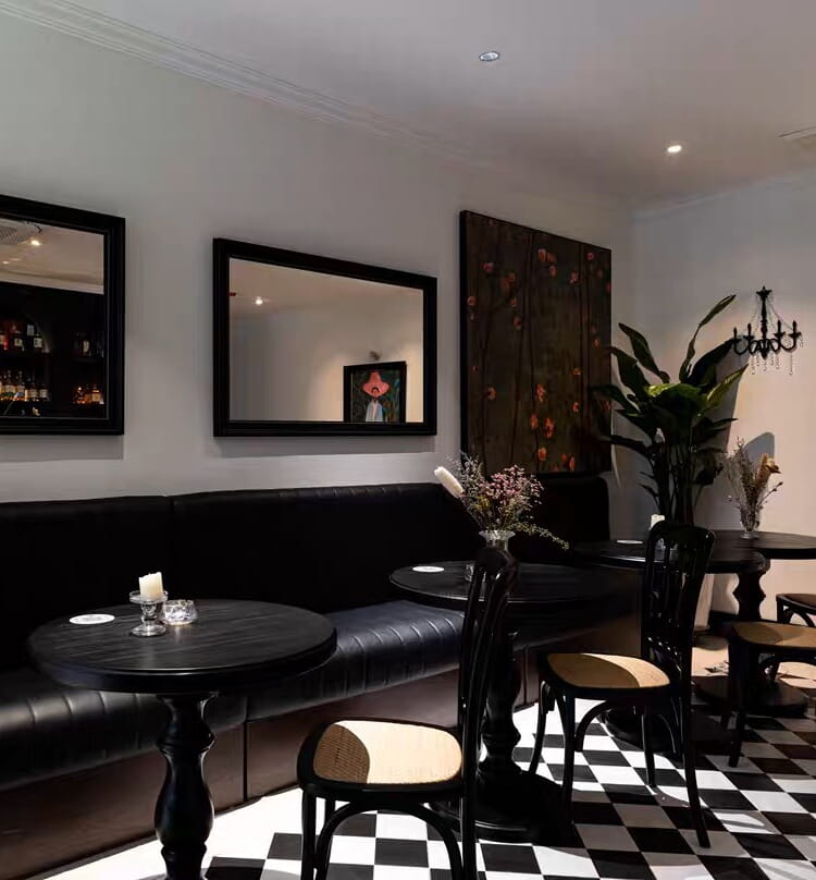 black leather booth with glossy finish and tufted upholstery paired with black wooden pedestal round accent table