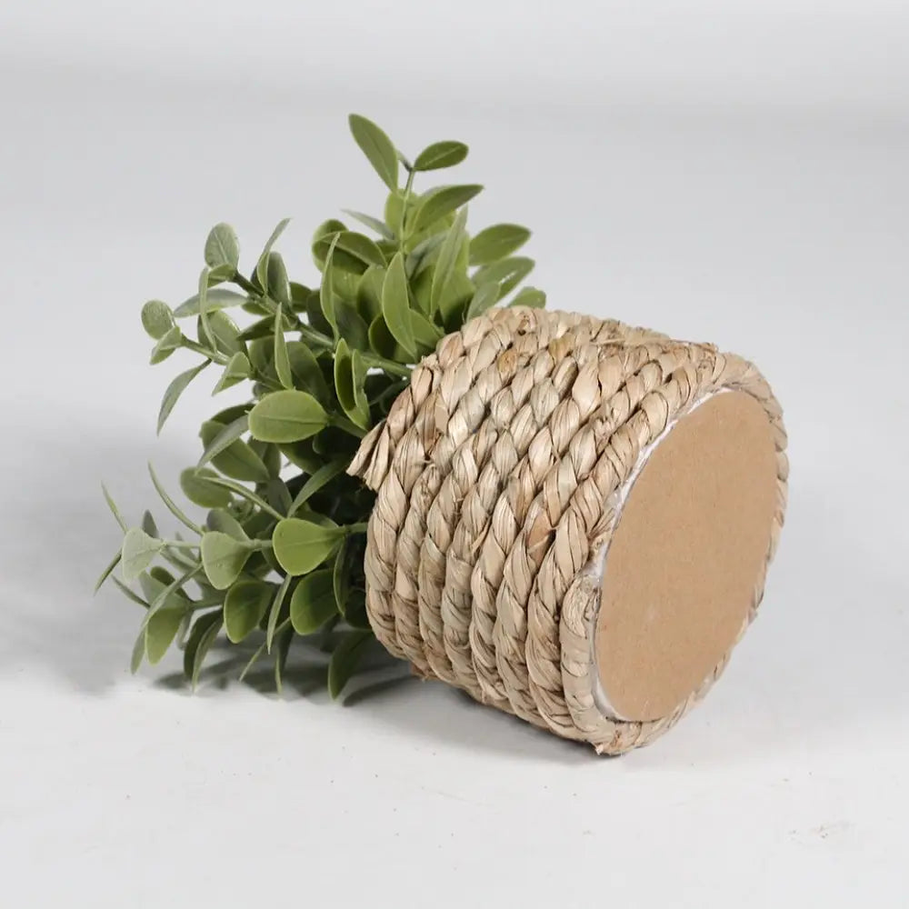Plante artificielle en pot d’eucalyptus de 11 cm dans un pot cylindrique en fibres naturelles enveloppé de corde, avec une façade extérieure beige clair texturée et un feuillage artificiel vert.