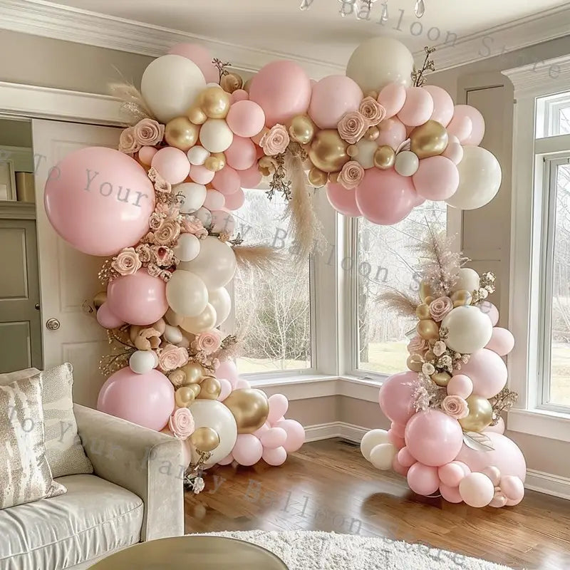 A decorative pink balloon arch kit for wedding and birthday parties featuring a mix of blush pink gold and white balloons adorned with floral arrangements.