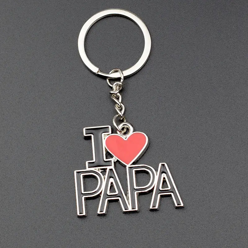 Schlüsselanhänger im Familienbuchstaben-Look aus silbernem Metall mit schwarz umrandeten Buchstaben und einem leuchtend roten Herz mit dem „I heart papa“-Anhänger.