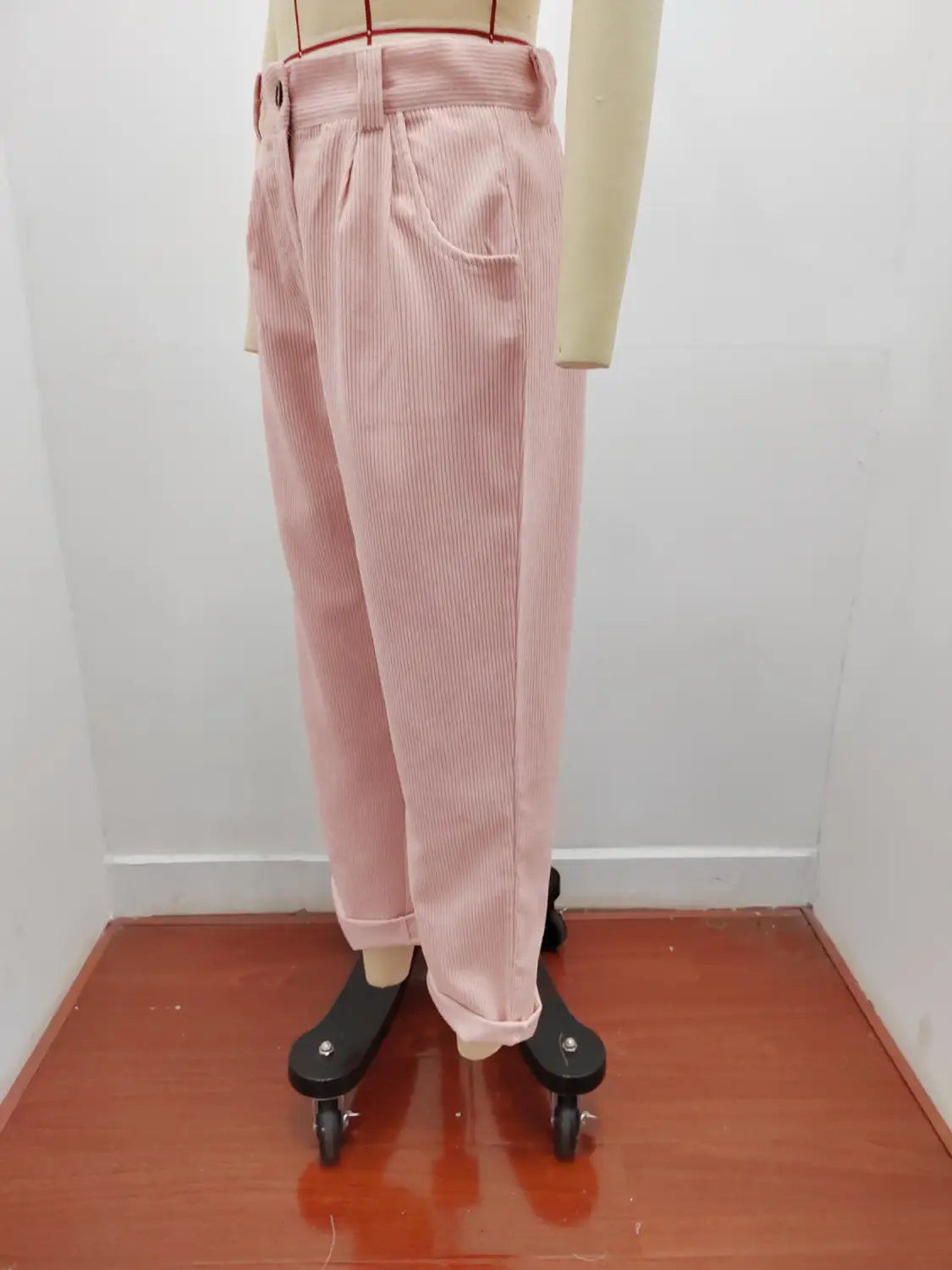 Pantalon en velours côtelé rose taille haute ample avec une texture côtelée verticale discrète et des bas retroussés.