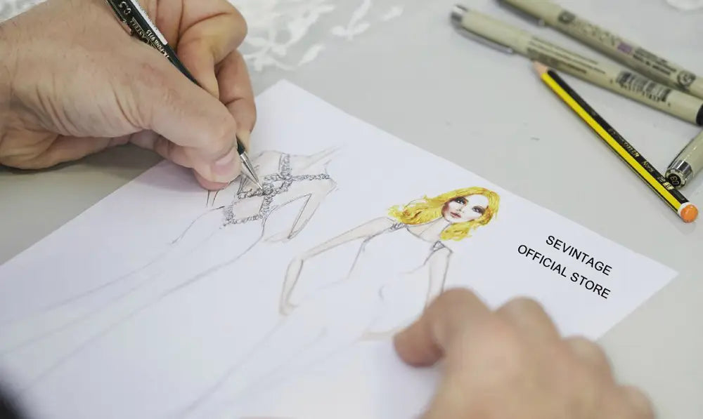Eine handgezeichnete Modeskizze auf weißem Papier einer Frau mit blondem Haar, die ein kunstvoll verziertes silber-schwarzes, mit Perlen besetztes maßgeschneidertes trägerloses A-Linien-Satinbodenlängen-Hochzeitskleid trägt.