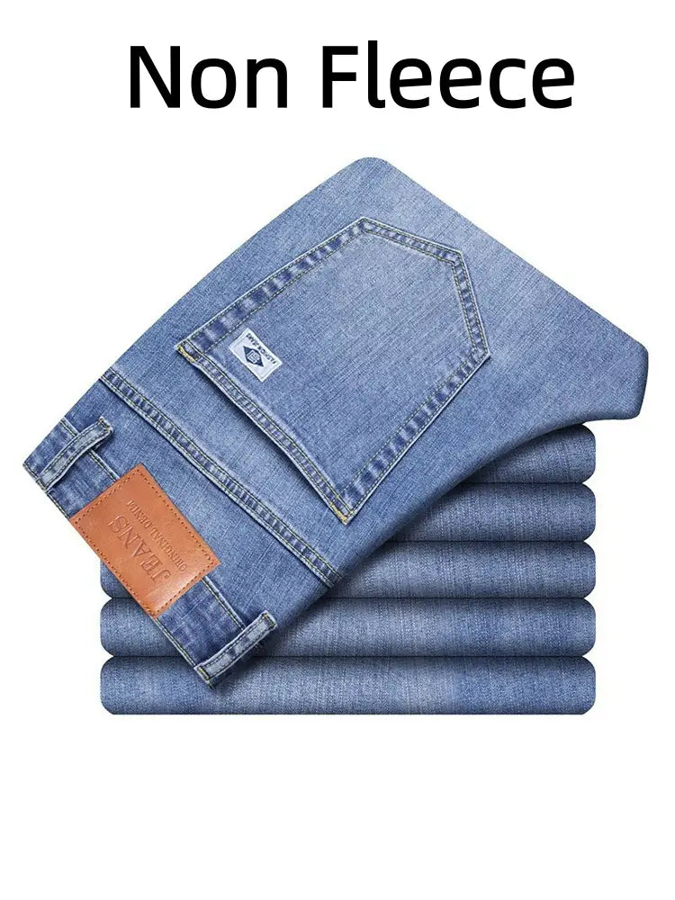 Un ensemble de jeans rétro délavés coupe droite ample pour hommes en denim bleu clair, soigneusement pliés, avec un empiècement de marque en cuir brun sur la ceinture.