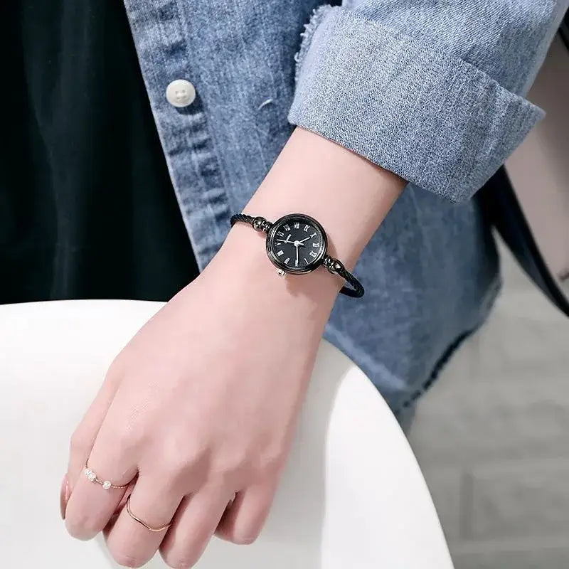 women stainless steel quartz bangle watch featuring a black round dial with roman numerals and a braided leather strap