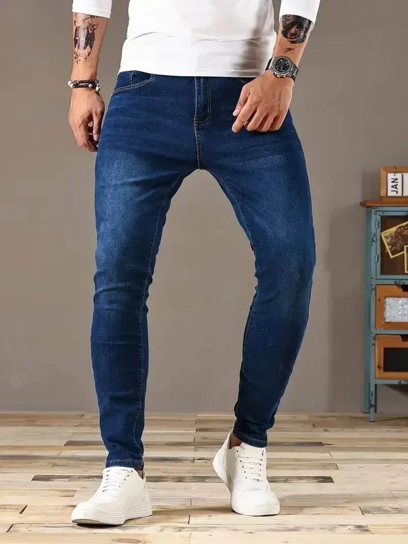 Jeans en denim bleu foncé coupe slim pour homme réalisés dans un denim coupe slim, avec un design classique à cinq poches et une atténuation subtile le long des cuisses.