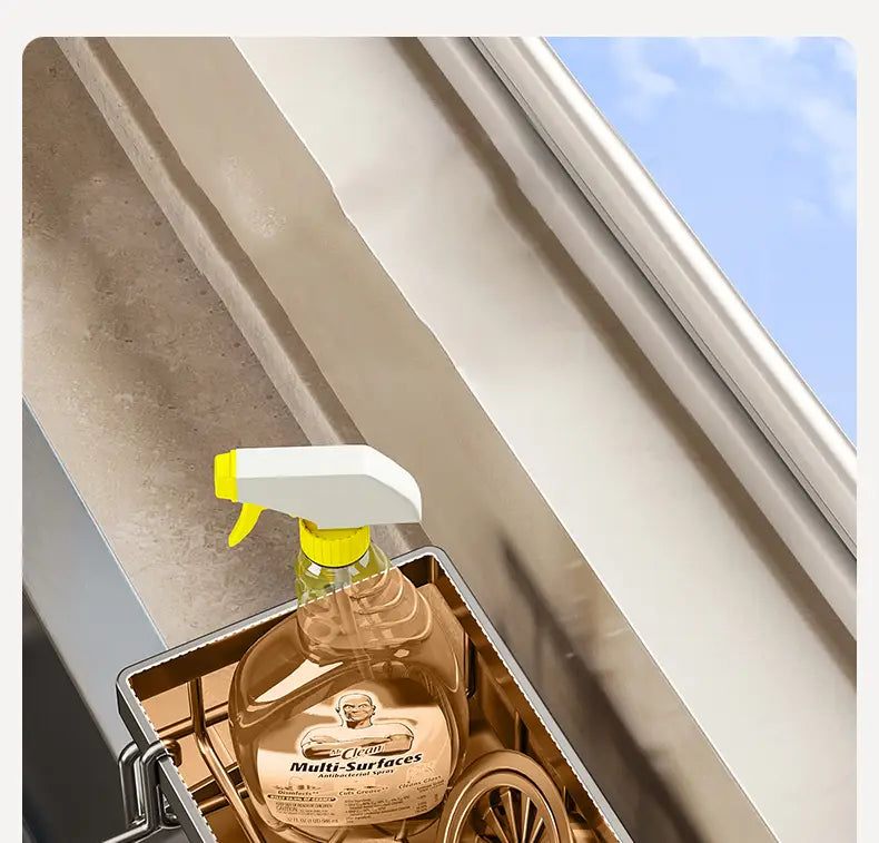 Botella rociadora de vidrio transparente con gatillo amarillo y boquilla blanca, etiquetada como «mr», en un organizador para fregadero de cocina de acero inoxidable.