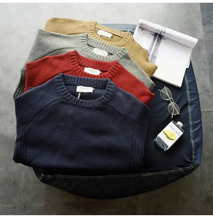 pile de cinq pulls en laine pour homme surdimensionnés, en maille décontractée, dans des tons terreux incluant bleu marine, rouge, gris et jaune moutarde.