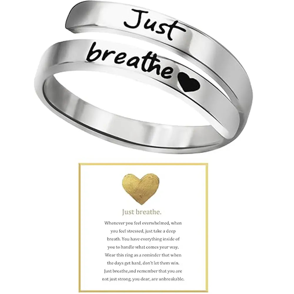 A sleek silver-toned stainless steel just breathe anxiety wrap ring engraved with black script and a small heart symbol.