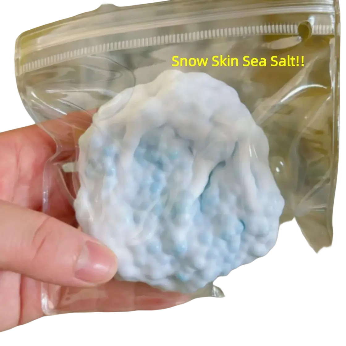 A light blue and white snow skin sea salt squishy toy in a clear plastic bag shown from the front