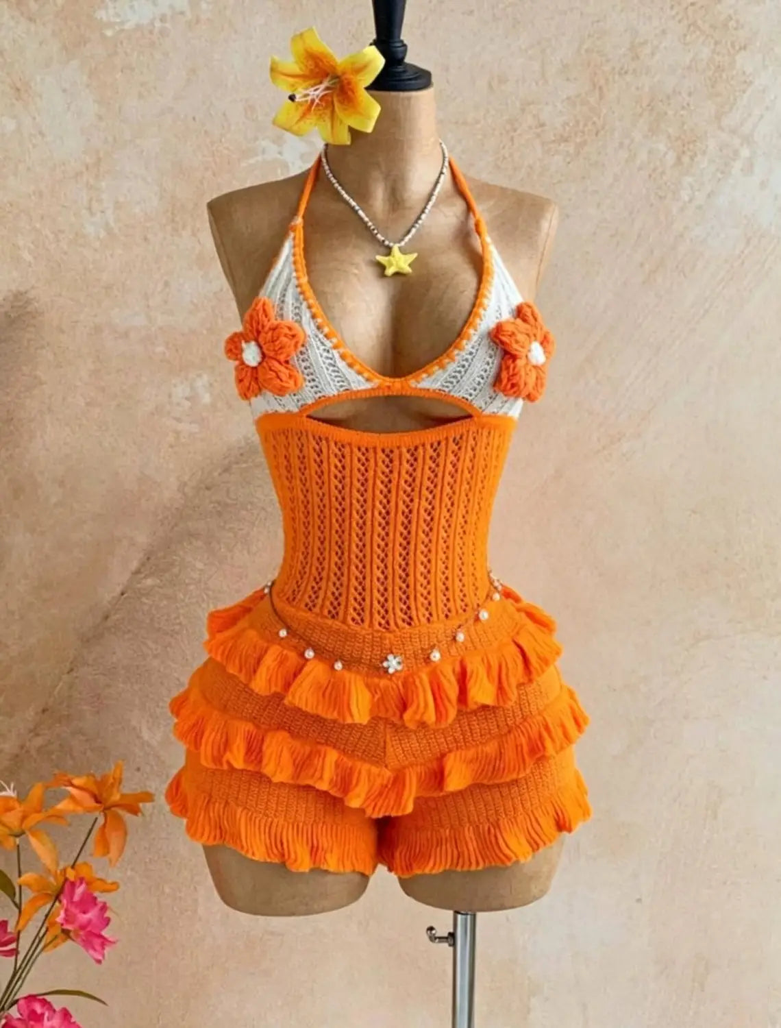 Orange knitted ruffle halter romper summer playsuit featuring crocheted halter top with ruffled shorts and floral embellishments.