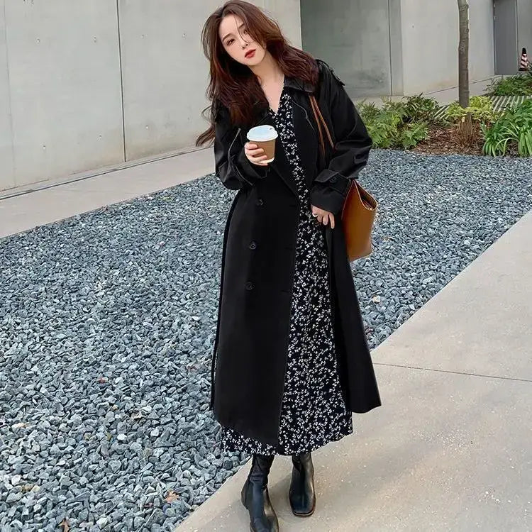 Black women double-breasted trench coat with a classic design and subtle texture worn over a floral dress for casual windbreaker use.