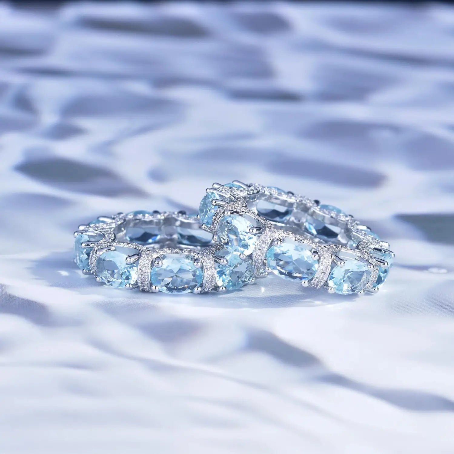 Elegant silver eternity band with oval-cut sky blue topaz stones and diamond accents from the Aquamarine Crystal bridal jewelry set.