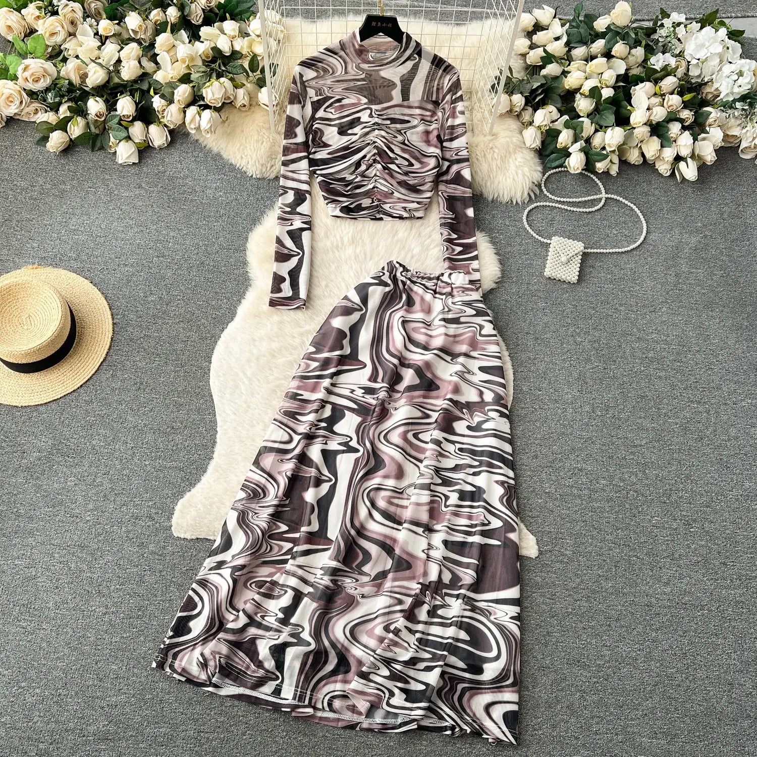 a two-piece mesh skirt set featuring a long-sleeved high-neck top and matching maxi skirt with an abstract marbled pattern in black white gray and muted pink with elastic closure.