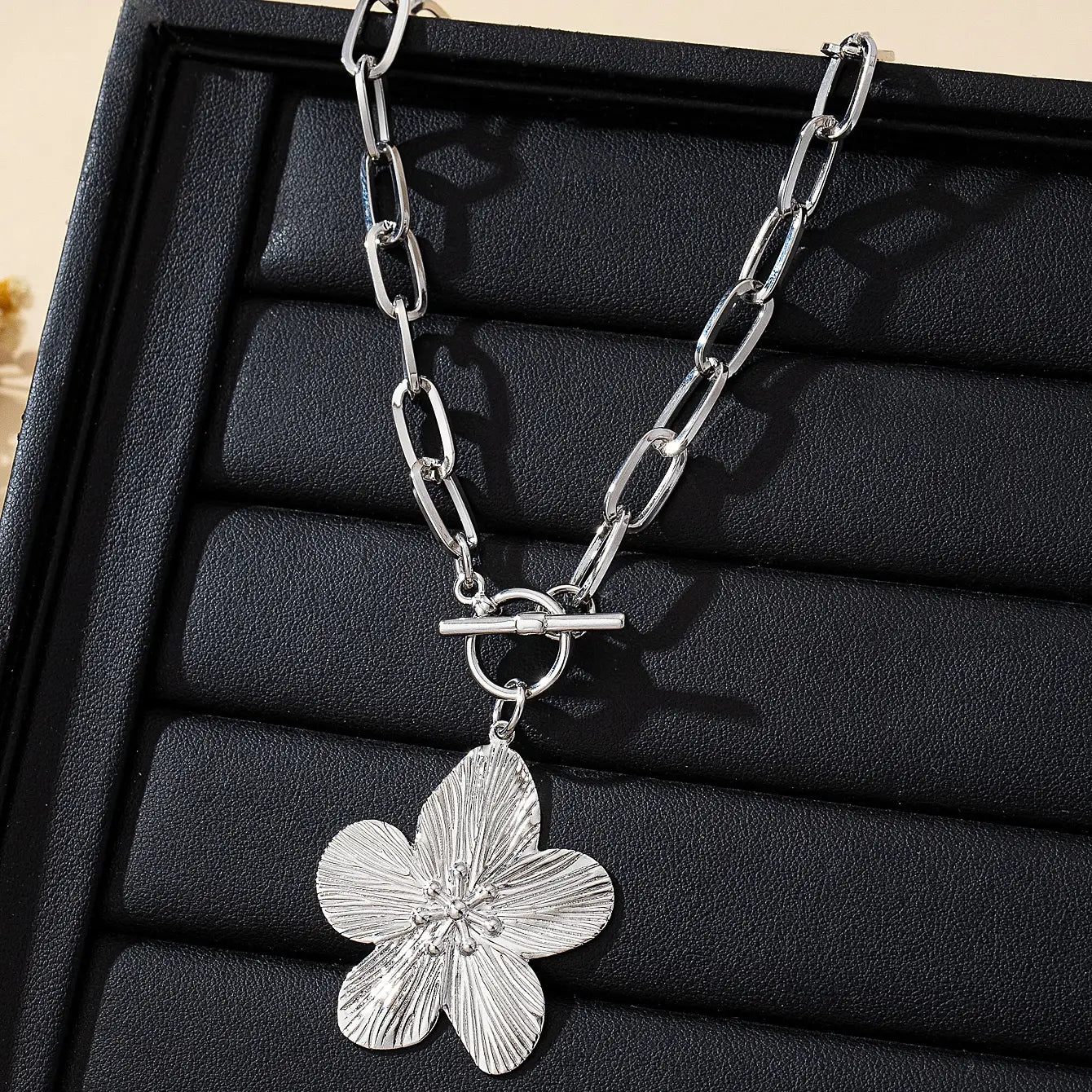 Collier pendentif à chaîne argentée avec un pendentif de fleur de glycine à cinq pétales texturé et une attache à bascule, style vintage pour femmes.