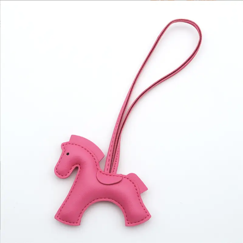 Porte-clés en cuir rose en forme de cheval avec lanière assortie, conçu pour transporter des clés ou décorer des sacs.
