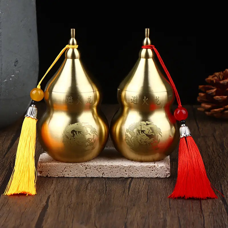 two golden brass gourd feng shui prosperity ornaments with engraved dragon motifs, one adorned with a yellow tassel on the left and the other with a red tassel on the right